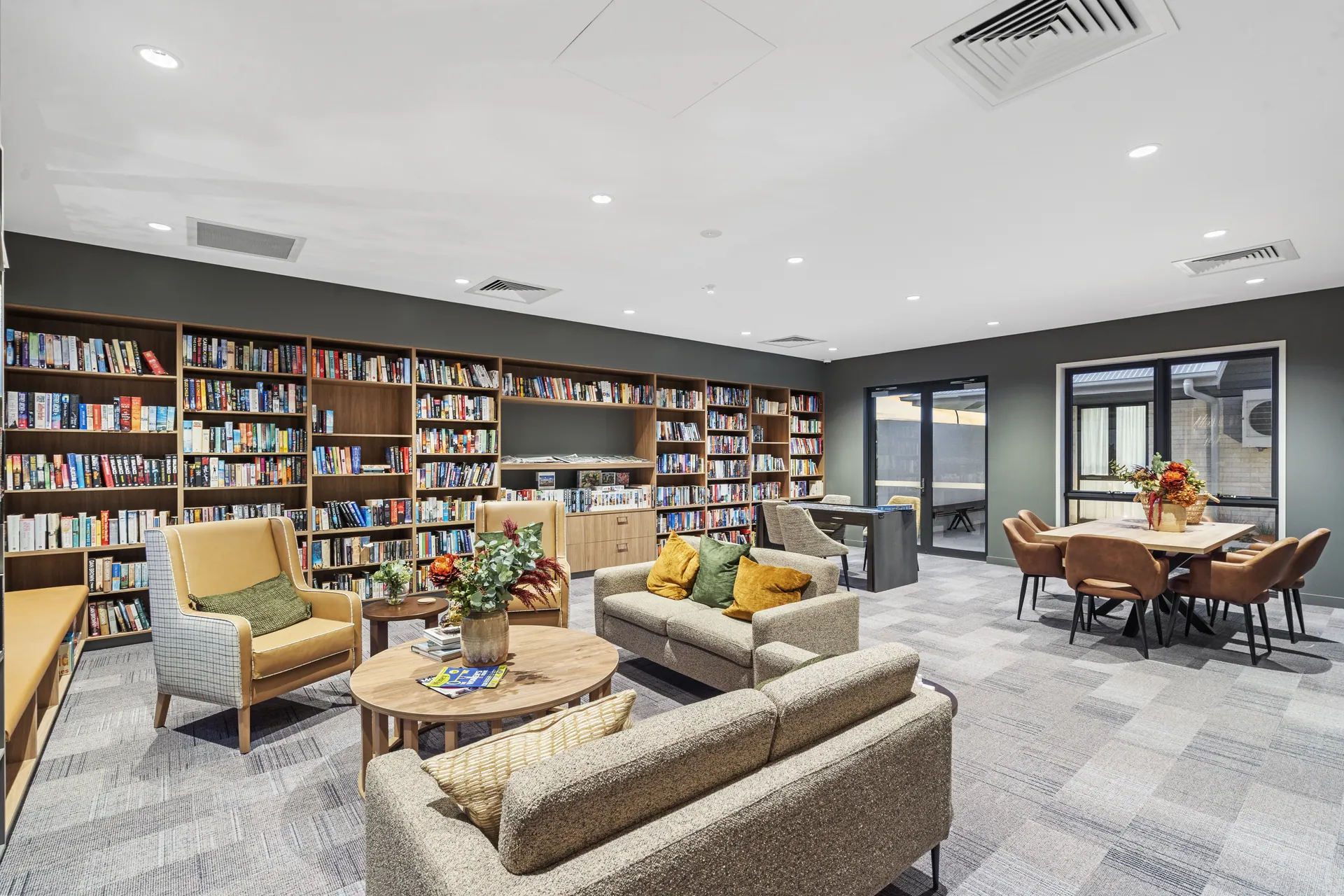 Residents' library lounge with built-in shelving and armchairs