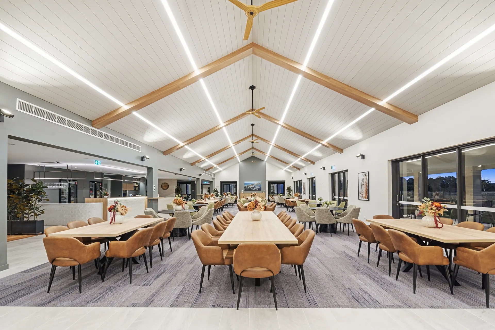 Communal dining hall with raked timber ceiling and linear lighting