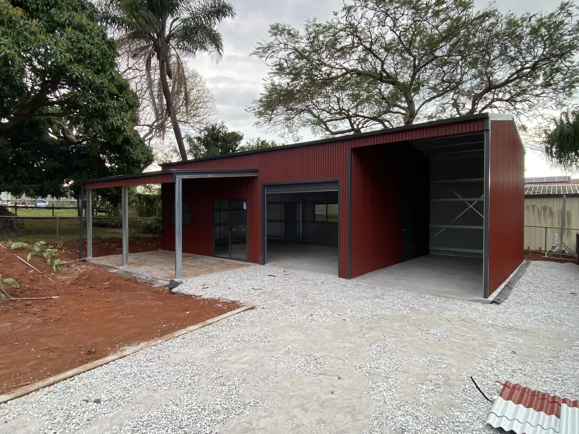 Red open-bay shed with gravel apron
